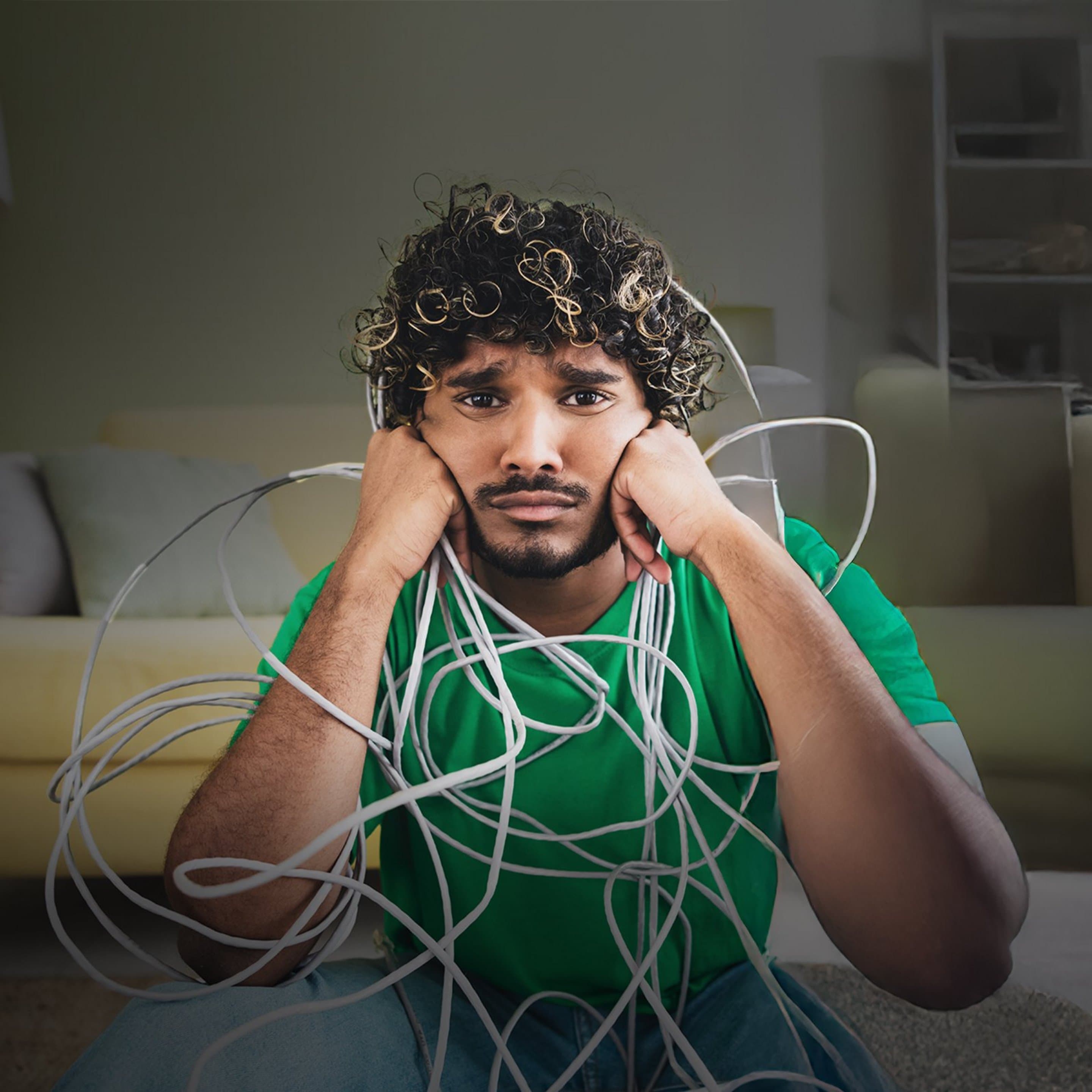 Bonn Kampagne Kabelsalat Person sitzt im Wohnzimmer und ist von verwickelten Kabeln umgeben