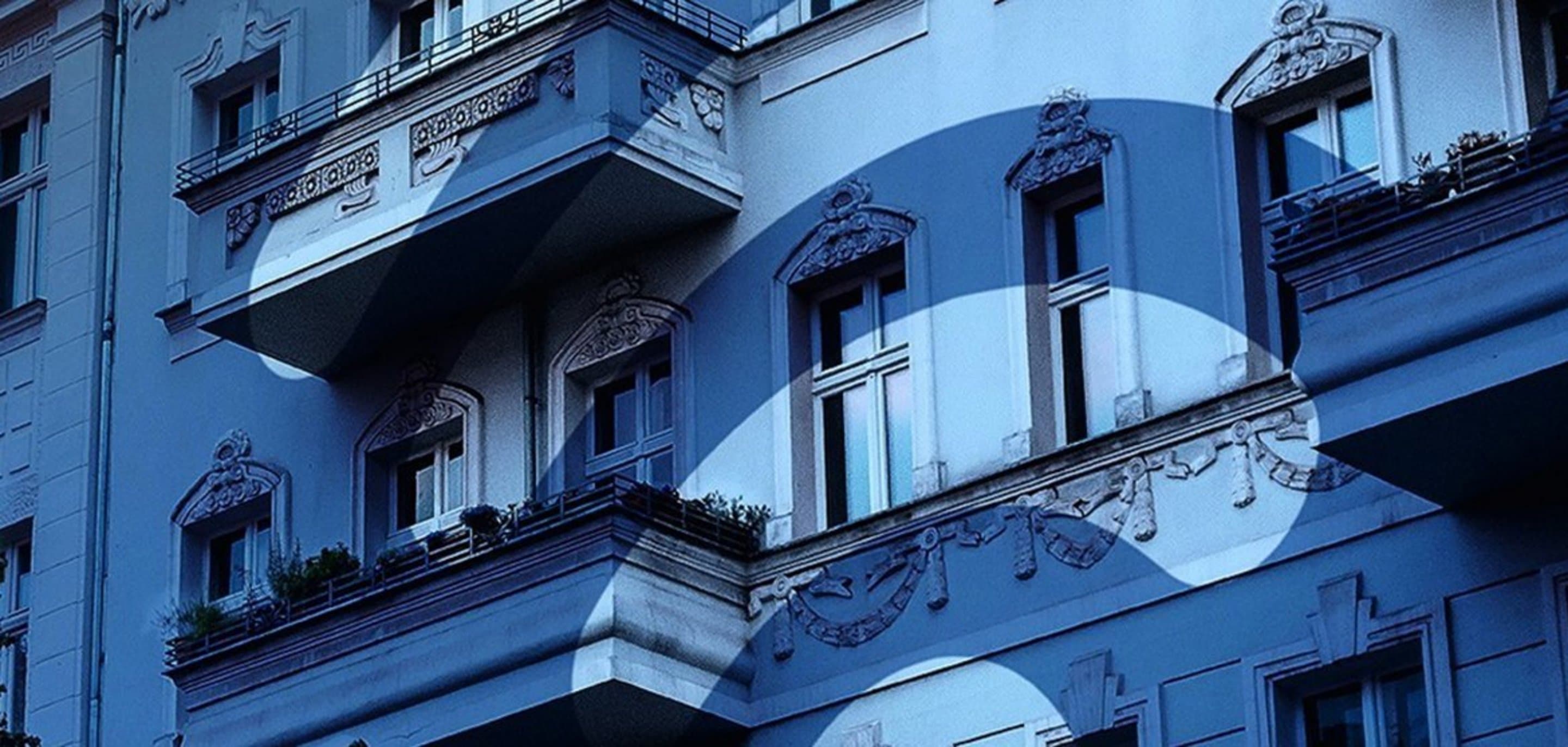 Häuserfront über die ein blauer Filter und ein WLAN-Icon gelegt ist.