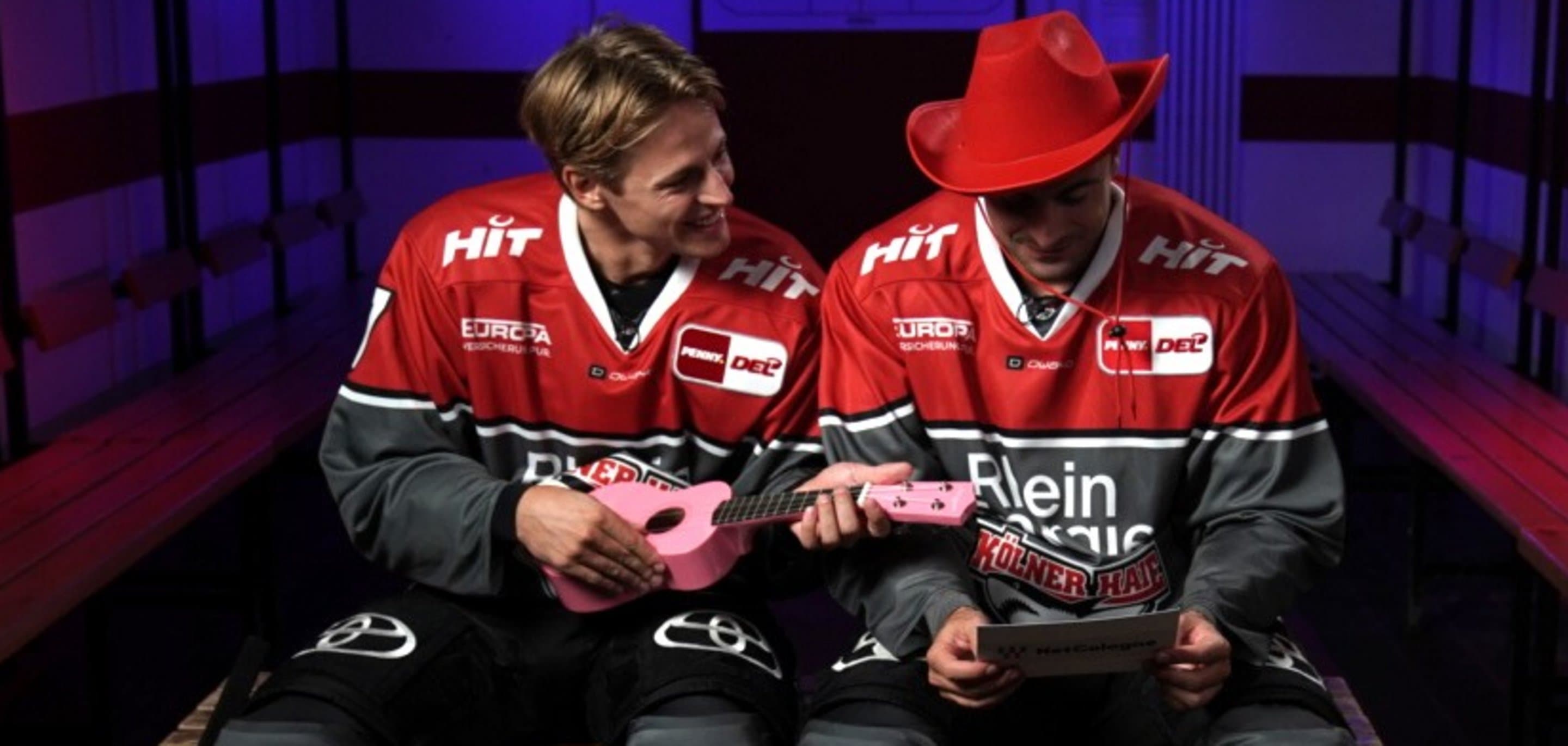 Zwei Spieler der Kölner Haie sitzen in der Umkleidekabine mit Karnevalsartikeln - Symbolbild für die Partnerschaft von NetCologne und den Kölner Haien