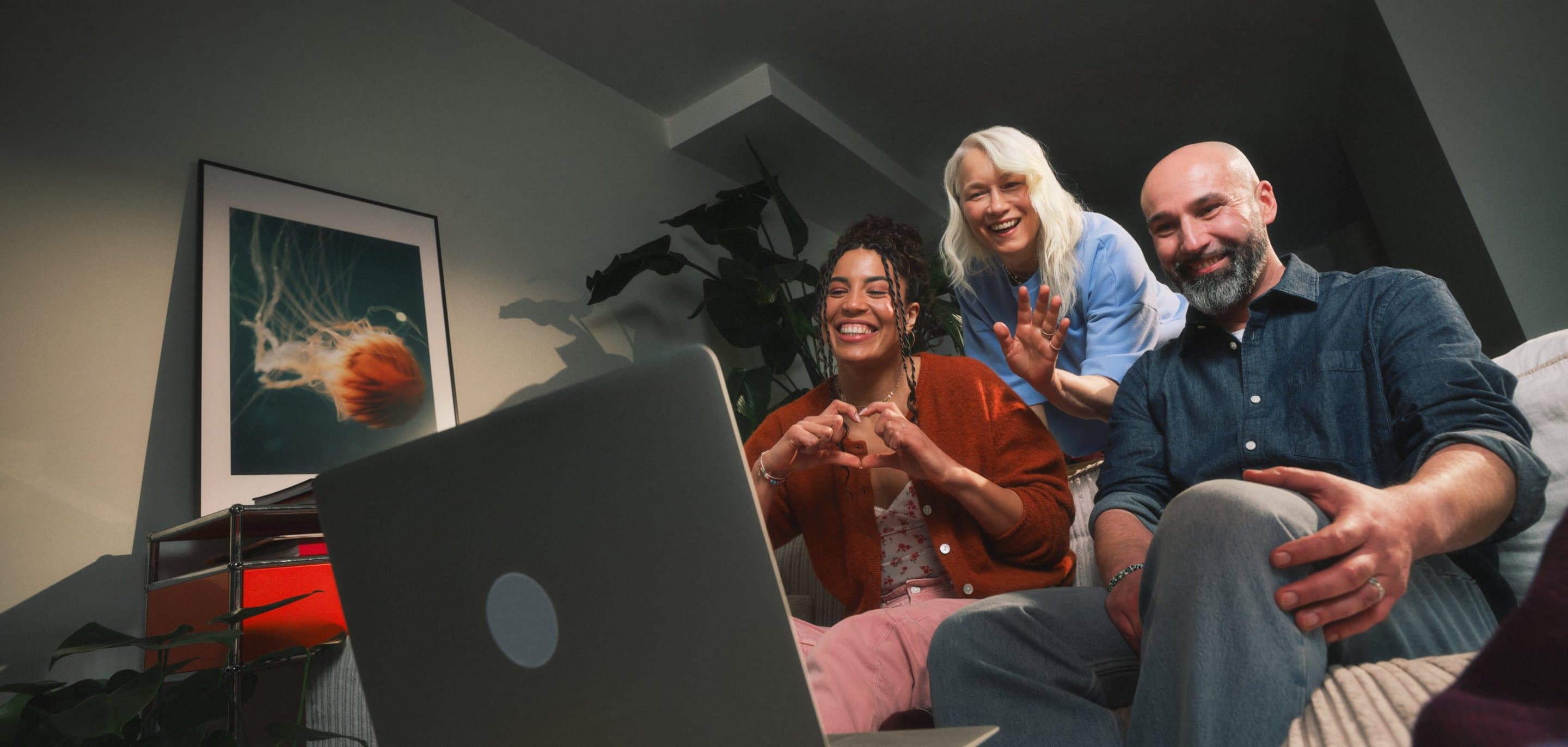 Mehrere Personen sitzen eng beieinander vor einem Laptop und machen verschiedene Handgesten in Richtung des Bildschirms.