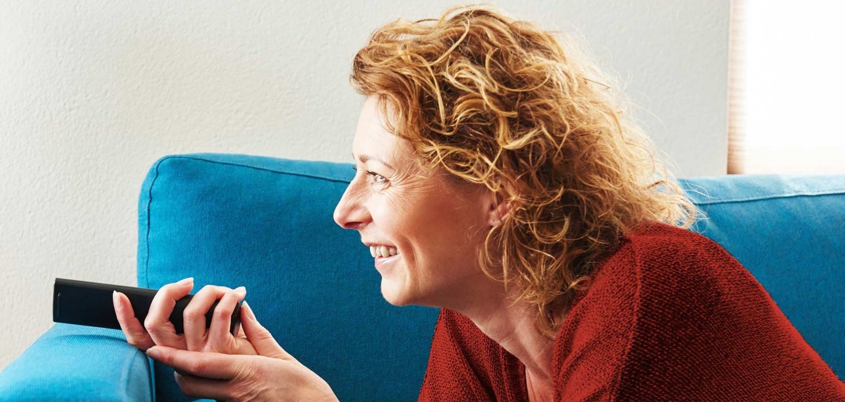 NetTV über Internet Speicheroptionen Frau liegt auf der Couch und hält Fernbedienung in der Hand
