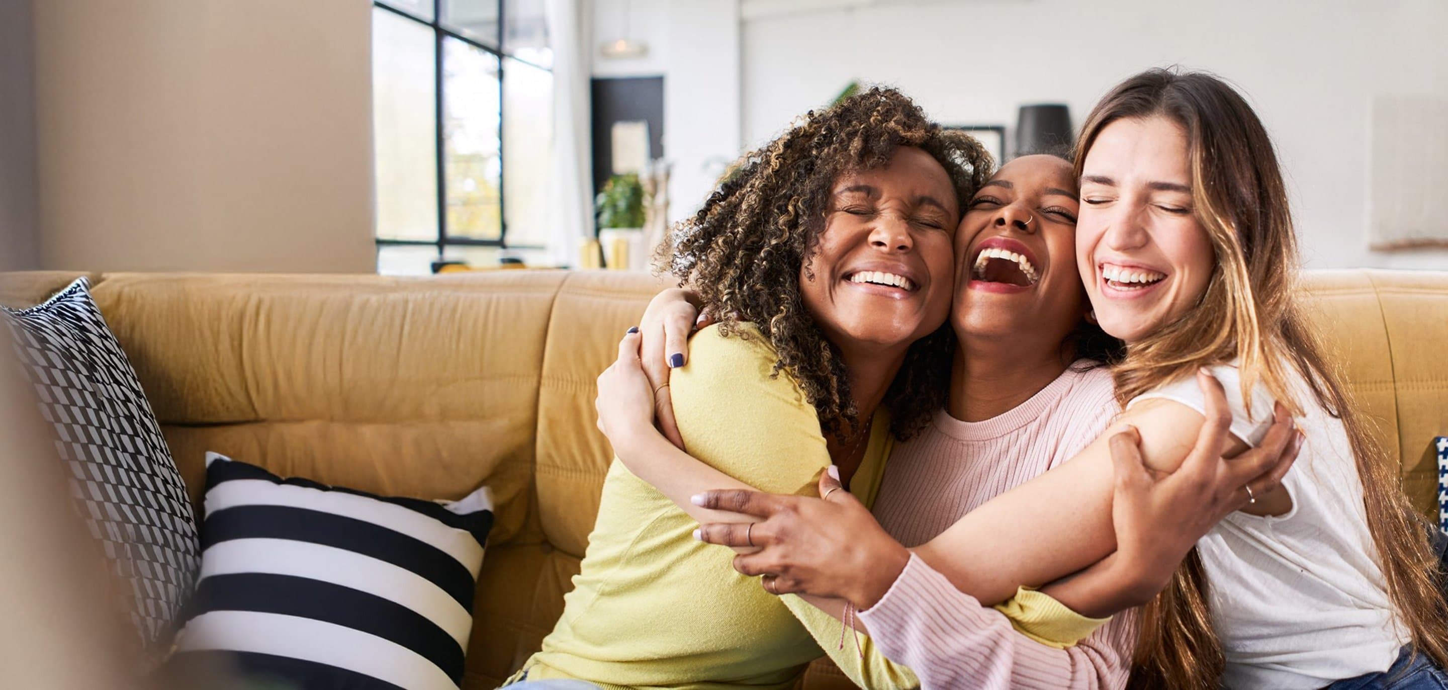 Freunde werben 100 € Prämie 3 Frauen sitzen auf der Couch und umarmen sich