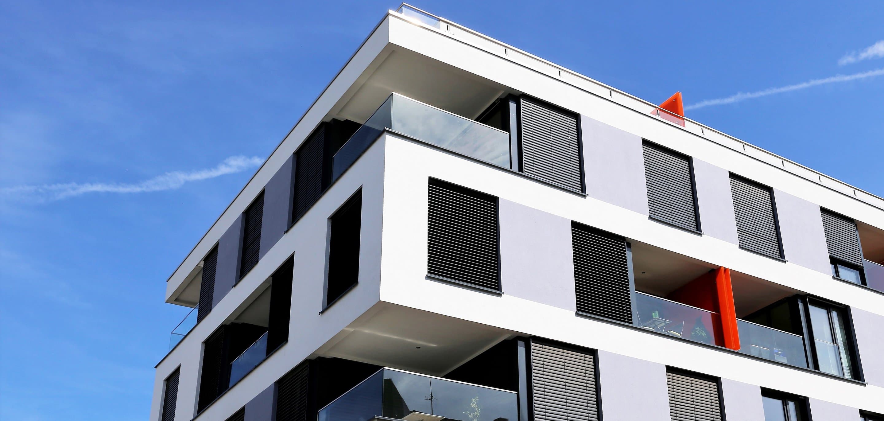 Modernes Gebäude mit roten Akzenten vor blauem Himmel - Symbolbild für Immobilienwirtschaft