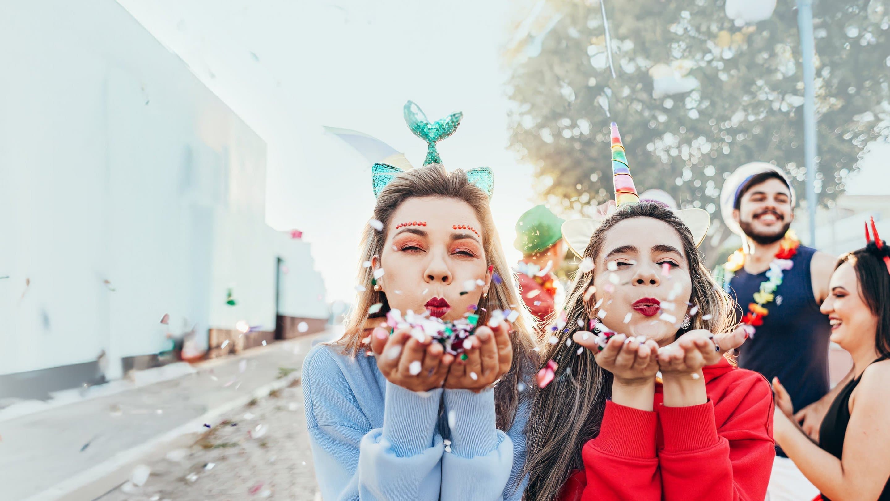 Freunde werben 200 Euro Praemie Zwei verkleidete Frauen pusten buntes Konfetti