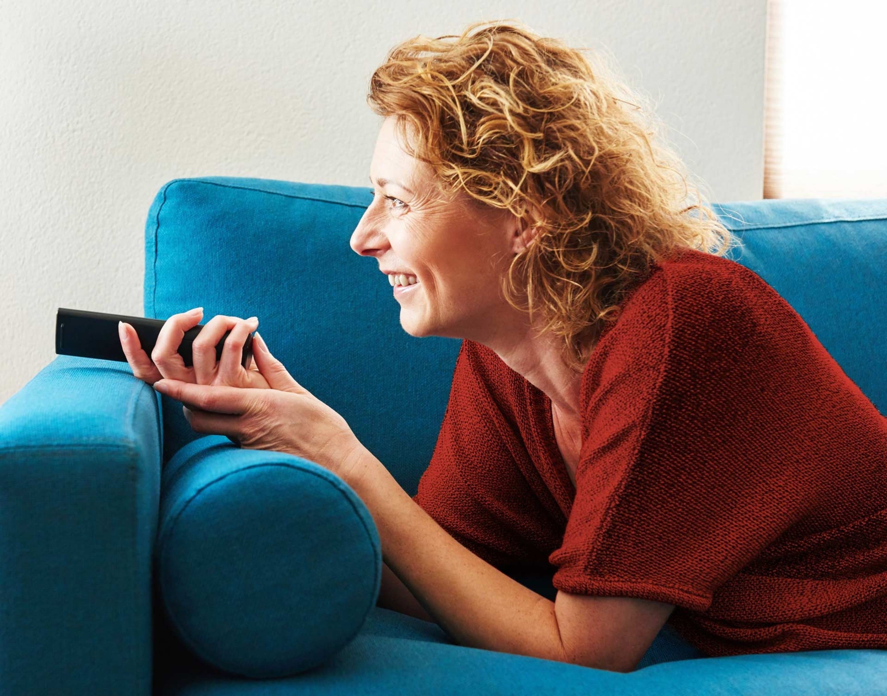 Zusätzlicher Aufnahmespeicher Frau auf der Couch liegend mit Fernbedienung in der Hand
