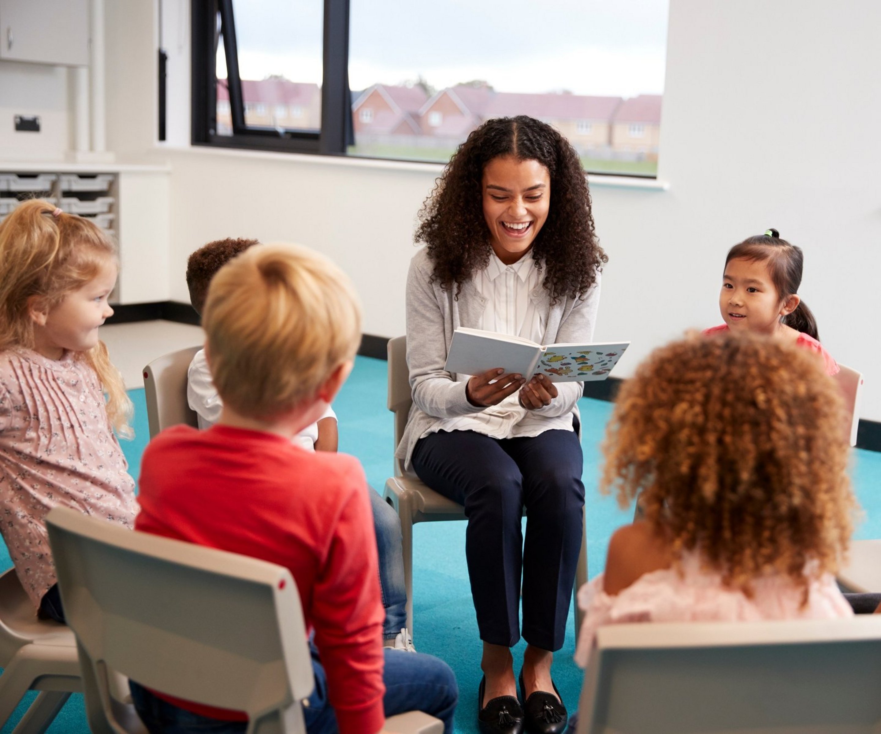 Klassenlehrerin liest Schülern aus einem Buch vor.